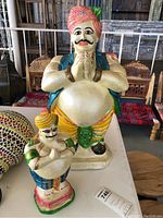 Two genie figurines in colorful attire made from plaster composite, showing full body details and relative size differences.