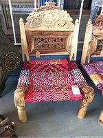 Front view of the Indian artisan folding low chair showing carved backrest and colorful woven seat.