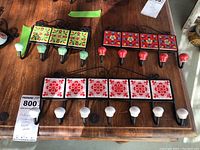 Three sets of Indian ceramic tile wall hooks arranged on a wooden surface, showing all hooks and tile designs