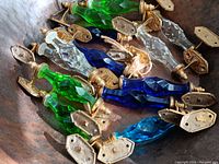 Photo showing nine faceted glass door handles in blue, green, clear, and turquoise with brass mounting hardware.