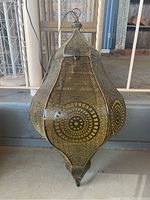 Front view of Indian painted tin filigree hanging lantern, showing full body and intricate perforated patterns in gold on dark metal.
