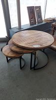 Three round nesting tables arranged stacked and nested, highlighting reclaimed wood tops and black metal bases.