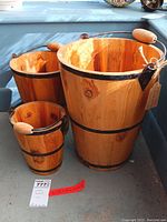 Full view of three handcrafted wooden buckets with natural wood finish, metal bands, and handles with wooden grips.