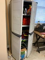 Full view of closed Rubbermaid plastic cabinet with gray handles and minor dents on doors.