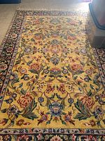 Full view of the rectangular rug showing the central gold floral pattern with green, red, and blue accents and a multicolor floral border.