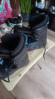 Pair of black FireFly kid's snowboard boots with blue detailing on a small table indoors