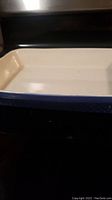 Photo showing the rectangular stoneware oven dish with cream interior and blue exterior rim.