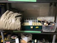 Air mattress folded and placed on shelving unit along with fishing tackle boxes and containers.