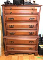 Front view of Krug maple wood tall dresser showing all drawers closed and brass handles.