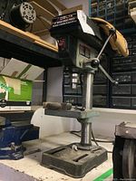 Front angled view of the Delta drill press showing the adjustable table and three-spoke depth control lever.