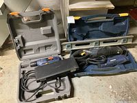 Ryobi drill and Mastercraft reciprocal saw with their cases and a metal level all displayed on the floor.