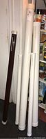 Five fishing rods in protective tubes, white and brown tubes standing upright
