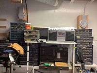 Wide shot showing multiple hardware organizer chests and a Sony boombox on a white shelving unit with other hardware parts and papers inside chests.