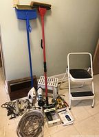Photo showing entire lot including step stools, cleaning tools, irons, power cords, hand tools, and boxed Garmin device.