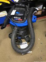 Mastervac wet/dry vacuum with attached flexible hose on floor, showing overall condition and label.