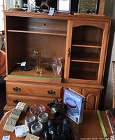 Two piece media cabinet showing the open upper left section with pull-out shelf, side wooden door cabinet without glass, and two lower drawers with brass handles.