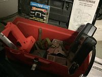 Photo showing red toolbox containing staplers, various staples, and a manual for Craftsman electric nailgun