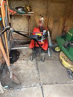 Full view of red tiller with black handles and front tines