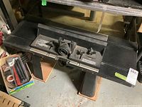 Top view of black plastic router table with central mounting area and adjustable knobs.