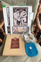 Full shot showing two framed memorabilia pieces wrapped in plastic, a stamp album, and two containers with assorted stamps.