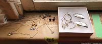 Wide view of assorted sterling silver jewelry including earrings and a necklace pendant on a wooden surface.