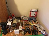 Photo of assorted tools, clocks, and small items including drafting set, screwdrivers, chisels, clocks, and flashlights arranged on a wooden surface.