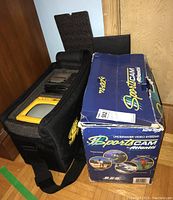 Photo of the blue and yellow padded carrying case for the SportsCAM underwater camera, alongside the original branded box showing wear and usage.