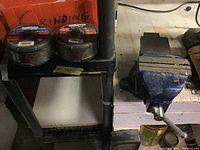 Two Mastercraft metal grinding wheels on shelf and a blue metal vise mounted on a workbench, showing general condition and arrangement.
