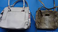 Photo showing both purses: a white Celine Dion purse with floral side panels and a tan faux snakeskin Nine West purse