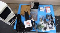 Photo displaying assorted computer peripherals and accessories including barcode scanners, cables, power adapters, fans, and boxed items.