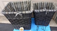 Two wicker laundry hampers with striped fabric liners on a blue surface.