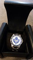 Toronto Maple Leafs wristwatch inside its black cushioned display case, showing the full watch face and metal strap.