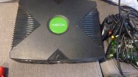 Original Xbox console top with green Xbox logo visible.