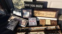 Photo of assorted wall signs in a cluster on ground showing various sizes and frames