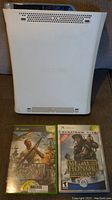 White Xbox 360 console with two Xbox 360 games, Medal of Honor Heroes and Medal of Honor Frontline Platinum Hits, shown front view