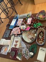 Photo showing a variety of costume jewelry items spread on a table including bracelets, rings, pins, necklaces, and a decorative floral heart-shaped box.