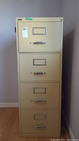 Front view of beige Artopex filing cabinet showing four drawers with label holders and chrome handles.