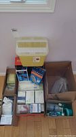 Photo of assorted medical aids: sharps container, glucose testing kits, boxes with syringes, swabs, sanitizer, and plastic urinals.