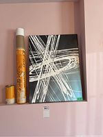 Lot with abstract acrylic painting displayed upright, showing full canvas with white brush strokes on black background, beside orange labeled poster tube and smaller roll.