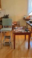 View of vintage green vinyl step stool chair next to laminate wood mission style side table.