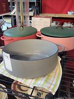 Three Great Jones iron pots shown, two pinkish with green lids and one gray without lid.