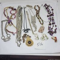 Full view of mixed jewelry lot showing necklaces, pendants, earrings, and brooches arranged on white background.