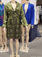 Two vintage coats displayed on mannequins; one silkey green patterned coat with buttons and the other blue suadey blazer-style coat.