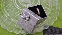 Ring in a silver decorative gift box with a silver bow, displayed on a glass plate.