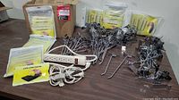 Overview of entire lot showing multiple packages of cleaning slime, power bar, extension cords, and scattered metal hooks.