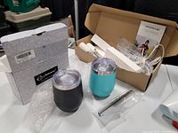 LED grow light components with packaging, travel tumblers in black and turquoise with lids, metal straws and cleaning brush in plastic bag.