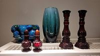Full front view including all items: ruby red glass candlestick holders, decanter bottles, salt and pepper shaker bottles, blue ceramic footed planter, and blue-green pottery vase.