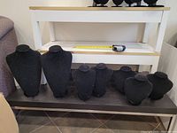 Seven black velvet necklace display forms arranged on a black table, showing the full lot and approximate scale with tape measure in background.