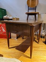 Angled front view of vintage mid-century modern wood side table with single drawer and tapered legs with metal foot caps.