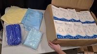 Open box showing 10 packages of KN95 masks each with 50 masks inside, totalling 500 masks. Four non-medical gowns in assorted colors (yellow, light blue, dark blue) displayed around the box.